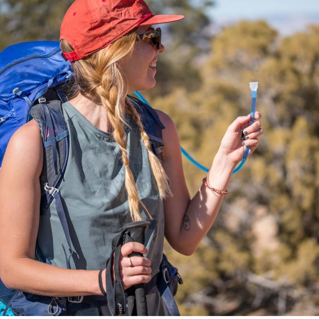 hiker drinking from platypus hoser reservoir bite valve during outdoor hiking trip with backpack