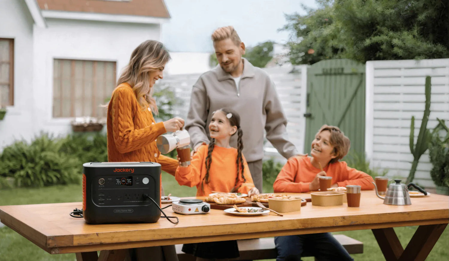 Jackery 1500 V2 power station powering outdoor family meal setup with portable stove and food.