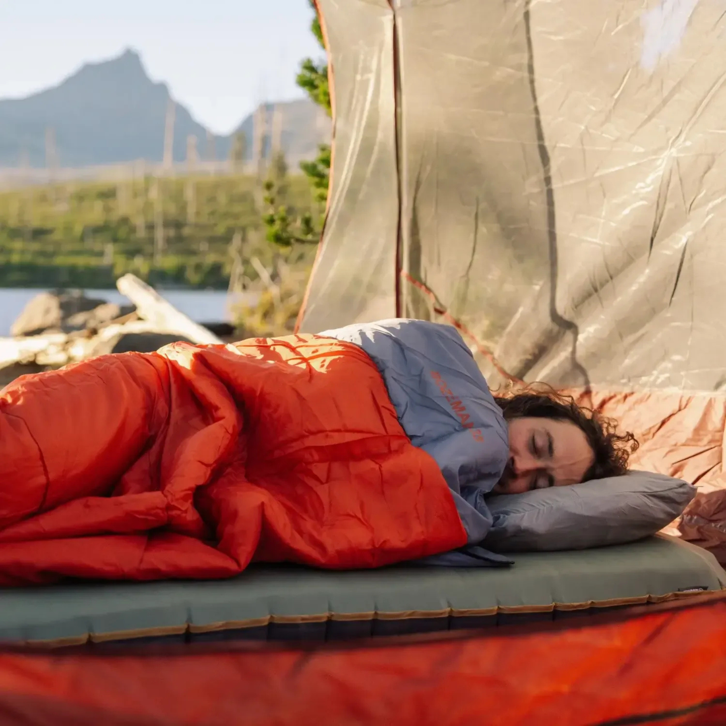 person sleeping outdoors in Klymit Bozeman 35 Large sleeping bag on sleeping pad in tent