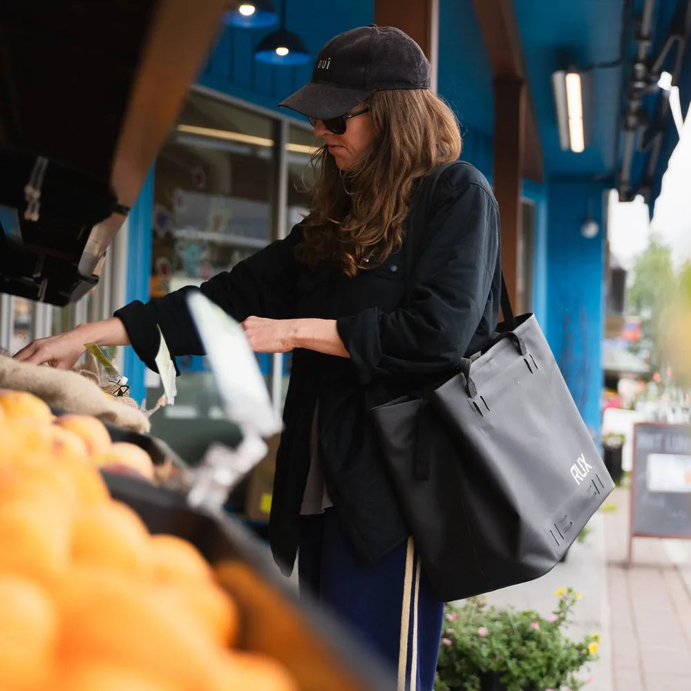 Person carrying a RUX waterproof tote bag while shopping outdoors