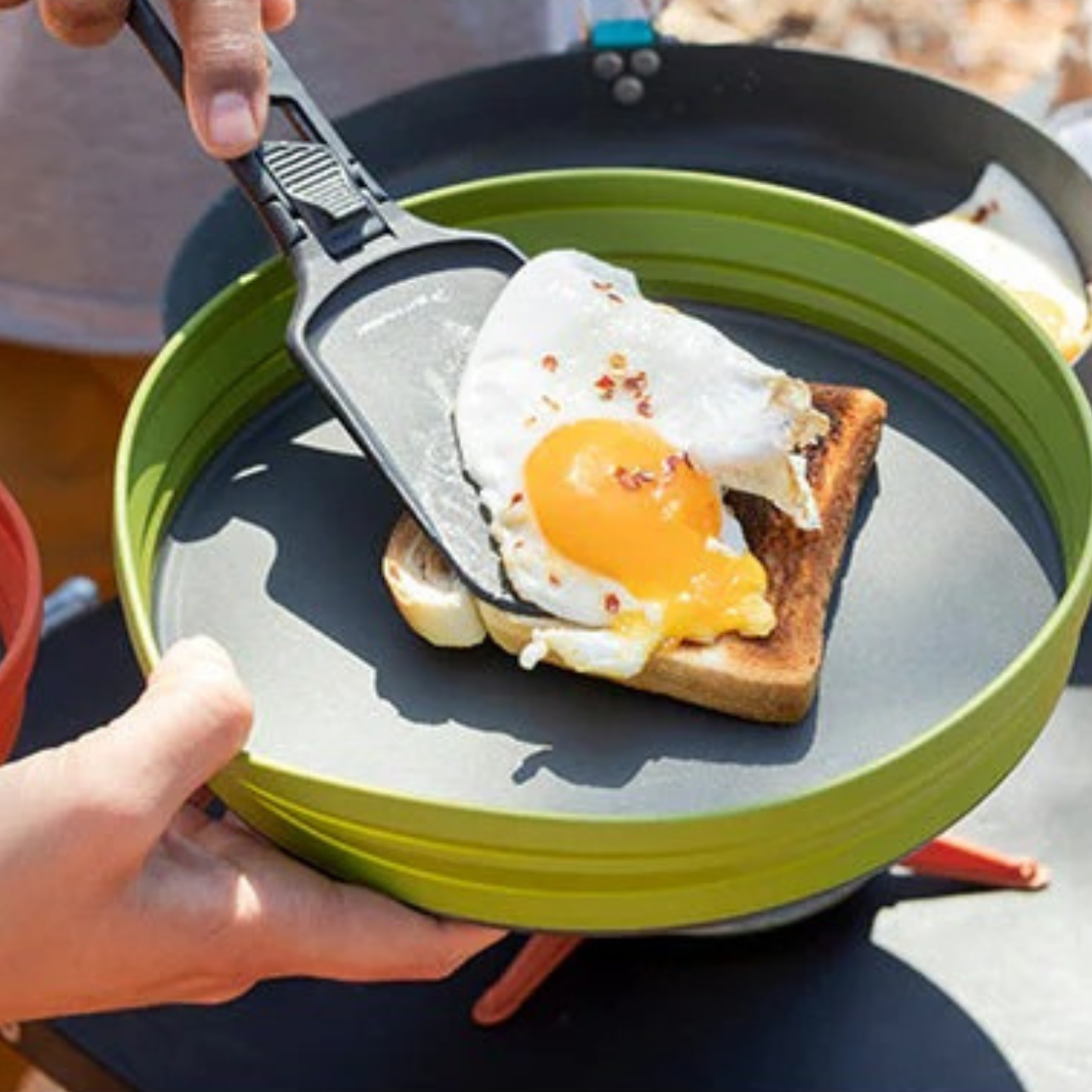 Sea to Summit folding spatula flipping fried egg on toast in camping skillet outdoors