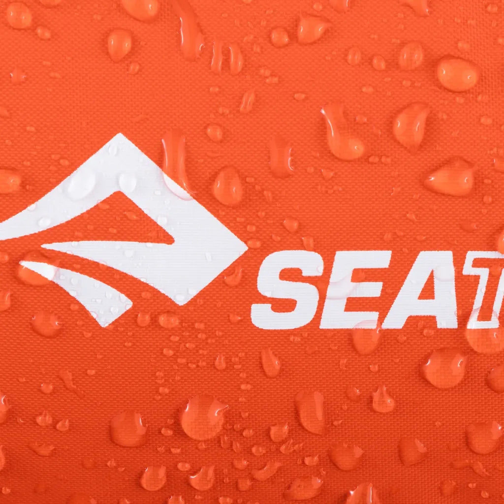 Close-up of water droplets beading on the orange waterproof fabric and printed logo of a Sea to Summit Lightweight Dry Bag