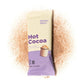 Alpine Start Hot Cocoa single cream and purple stick packet surrounded by loose cocoa powder spill on white background, showing Rich Cocoa and Creamy Oat Milk branding