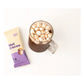 Alpine Start Hot Cocoa single cream and purple stick packet next to glass mug filled with hot cocoa topped with mini marshmallows on white background, showing serving suggestion
