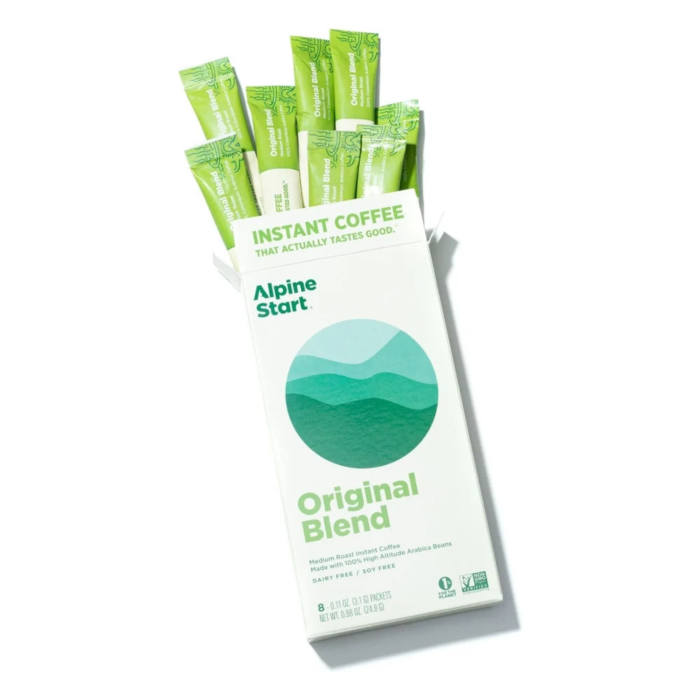 Alpine Start Original Blend instant coffee box open and tilted on white background revealing 8 green Original Blend stick packets fanning out with Instant Coffee That Actually Tastes Good tagline visible inside lid