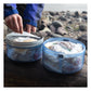 Two BVONE bear canisters open and filled with food bags on a log at a rocky shoreline, showing center divider organization system and expanded food storage capacity for multi-day backpacking