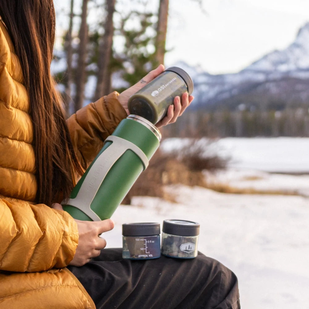 Pouring food from GSI Outdoors Glacier insulated travel stack in outdoor setting