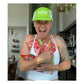 Enthusiastic female athlete wearing a green Huma Powered by Nature cap and white sports top laughing with multiple red Huma Chia Energy Gel Strawberry packets taped to her torso and arms, indoor lifestyle setting