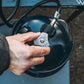 Hand turning the valve on an Ignik Gas Growler 3.8 lb refillable propane tank connected to a propane hose regulator