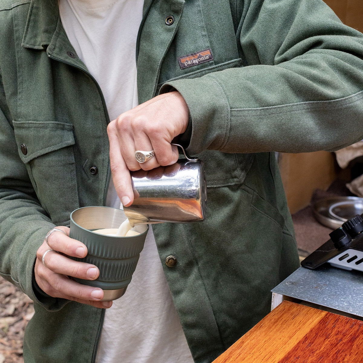 Hand picking up a Sea to Summit Detour collapsible cup from the stacked dinnerware set
