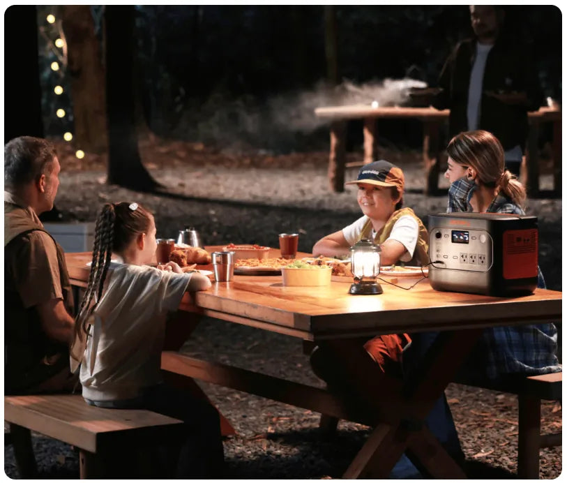 Jackery 1500 V2 power station powering lights during family camping dinner at night outdoors