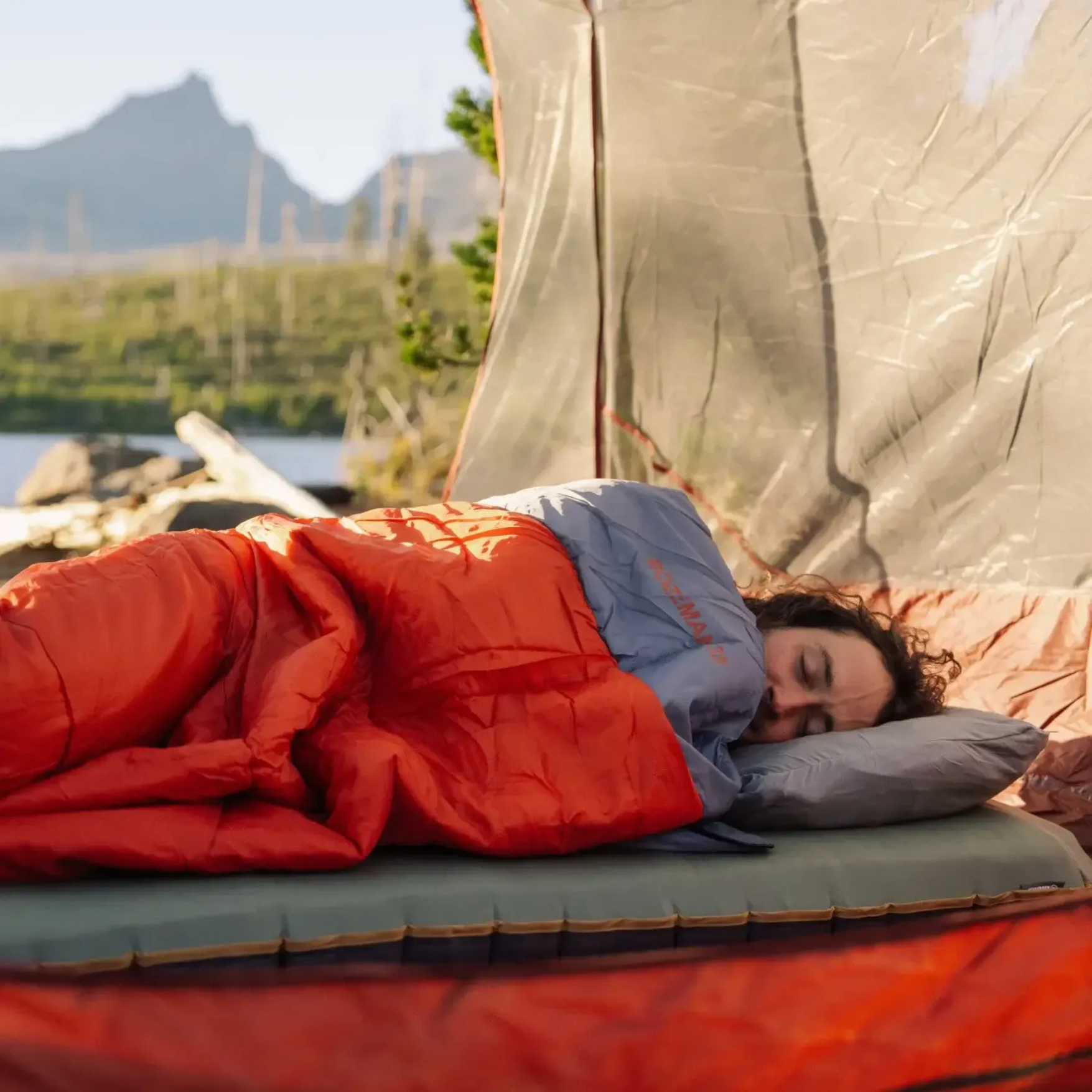 person sleeping outdoors in Klymit Bozeman 35 Large sleeping bag on sleeping pad in tent