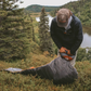 Camper rolling and packing Klymit Insulated Klymaloft Peak XL sleeping pad in outdoor backcountry setting