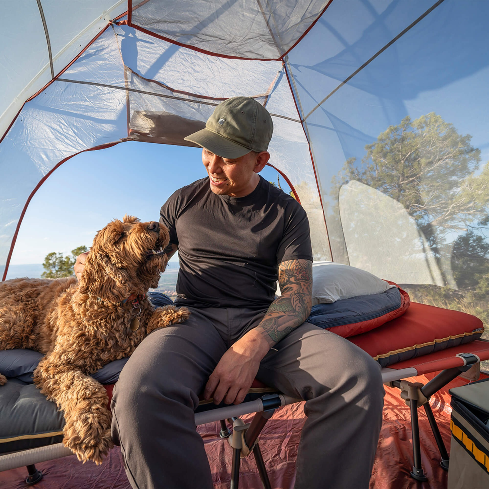 Camper relaxing inside tent on Klymit Insulated Klymaloft Peak XL sleeping pad with dog showing comfort and space
