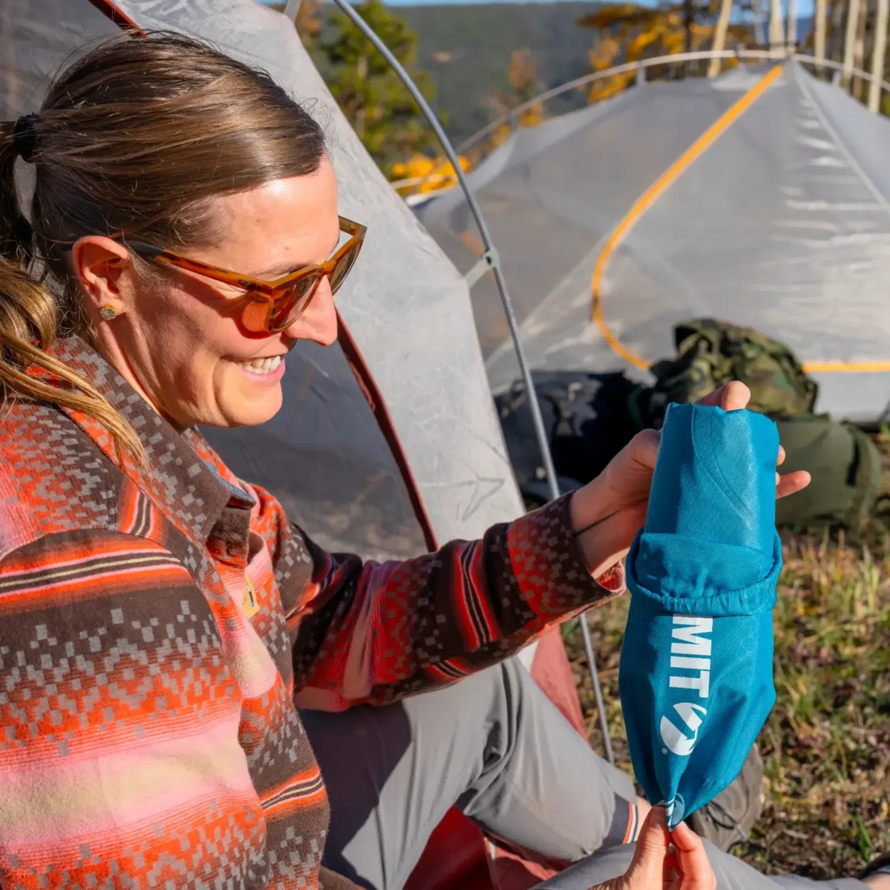 Camper unpacking Klymit Static V Base sleeping pad at campsite near tent
