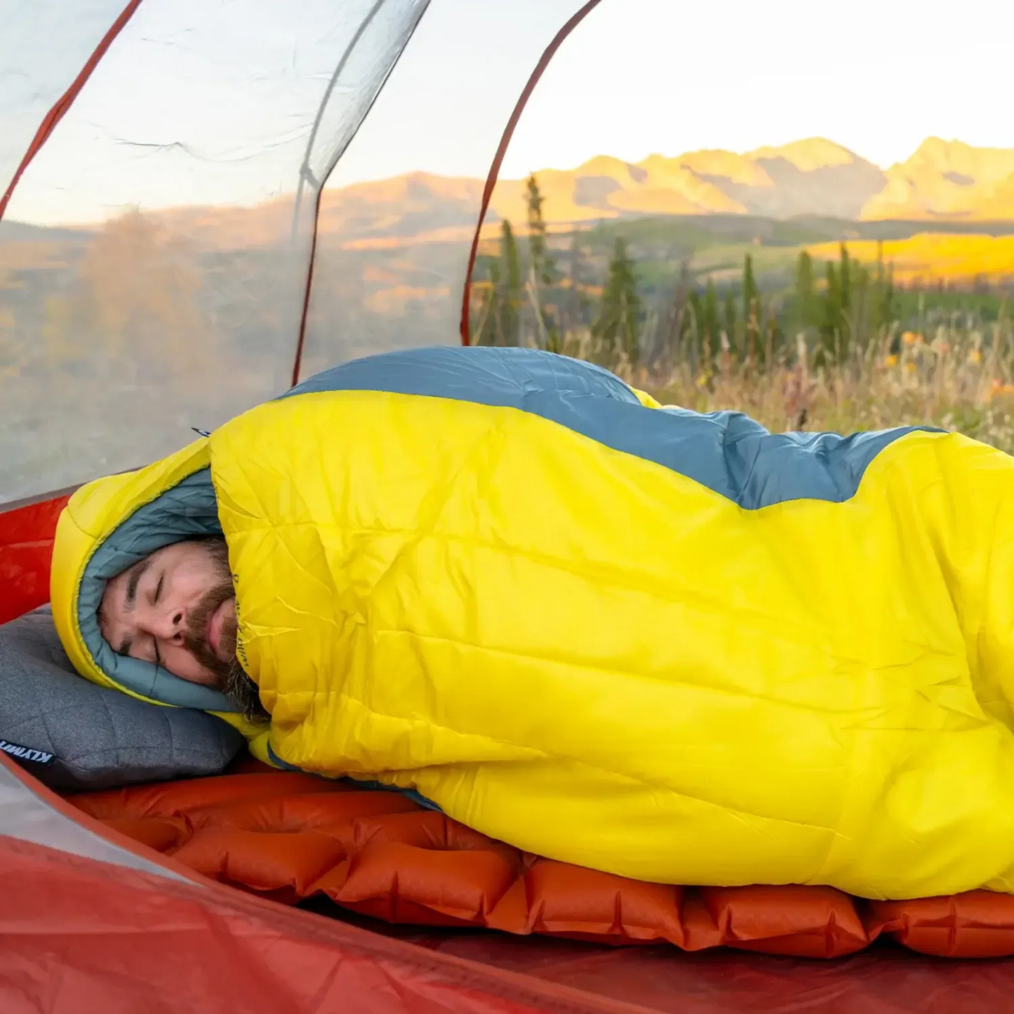 Person sleeping in Klymit Wild Aspen 0 sleeping bag inside tent during outdoor camping