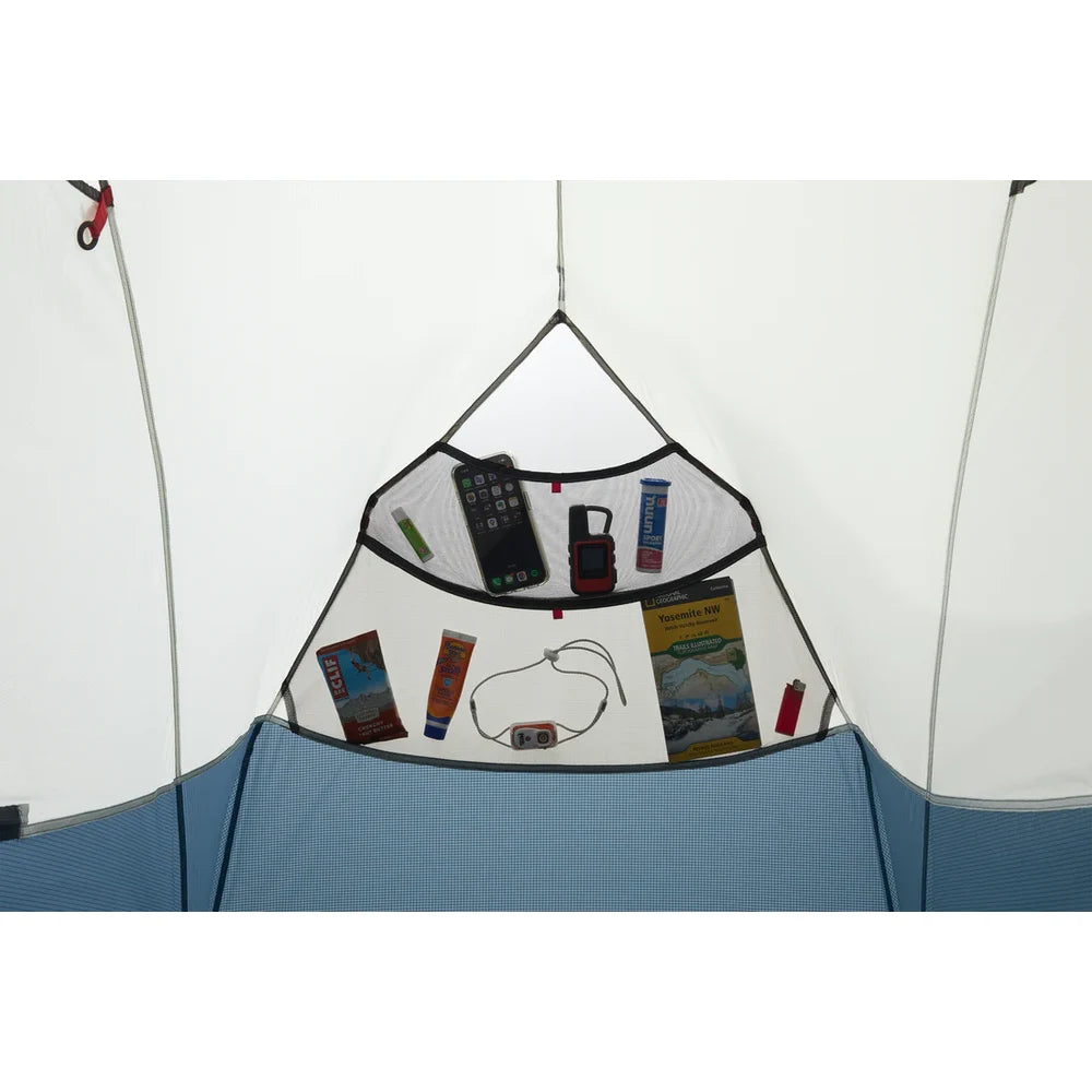 Interior gear pocket of MSR Hubba Hubba HD 1 tent filled with phone, GPS, map, snacks and lip balm showing generous single-person storage organization
