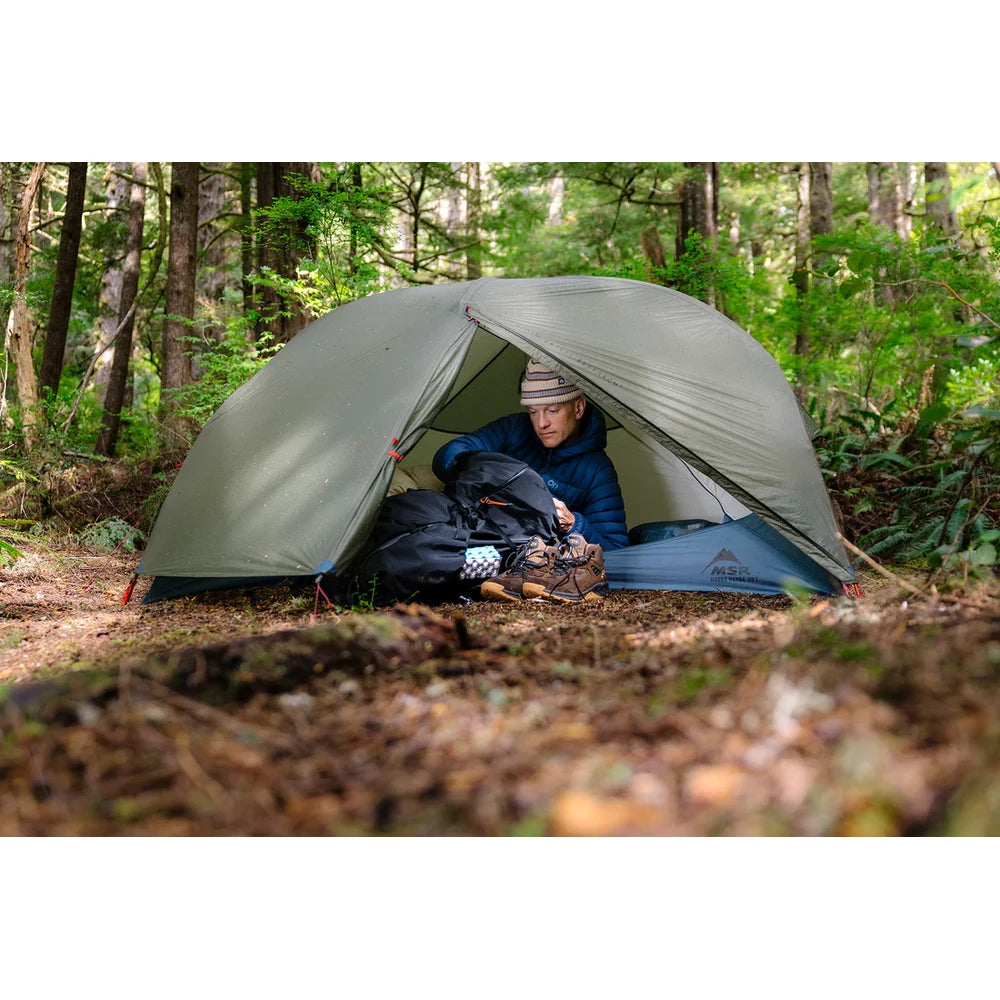 Solo backpacker relaxing inside pitched MSR Hubba Hubba HD 1-Person tent at forest campsite on Vancouver Island showing spacious single-person interior and vestibule