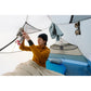 Woman hanging socks on MSR Hubba Hubba HD 2 tent interior clothesline with gear loft in use, sleeping pad and pillow visible in cozy 2-person interior