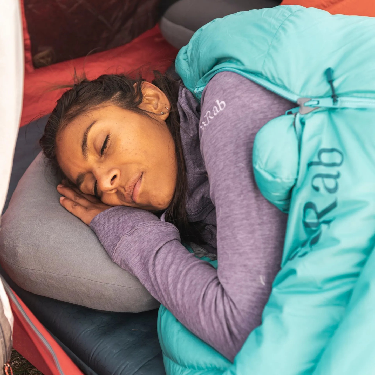 Person sleeping on Rab Stratosphere inflatable pillow inside tent during camping trip