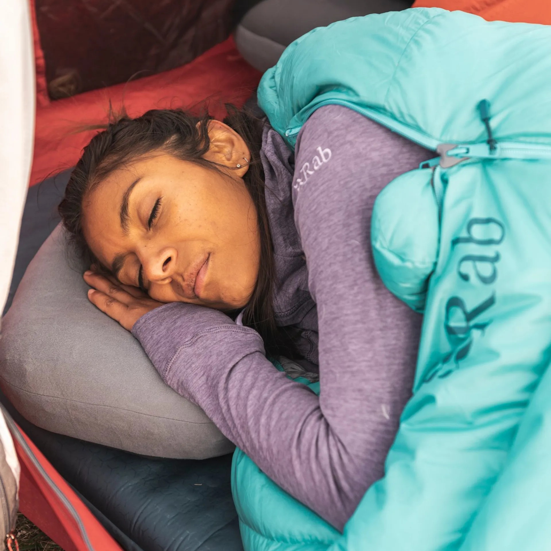 Person sleeping on Rab Stratosphere inflatable pillow inside tent during camping trip