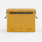 Rux 70L Press-Seal bronze container rear panel view showing streamlined hard-sided body, reinforced rail, and vent slots.