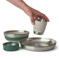 Hand picking up a Sea to Summit Detour collapsible cup from the stacked dinnerware set