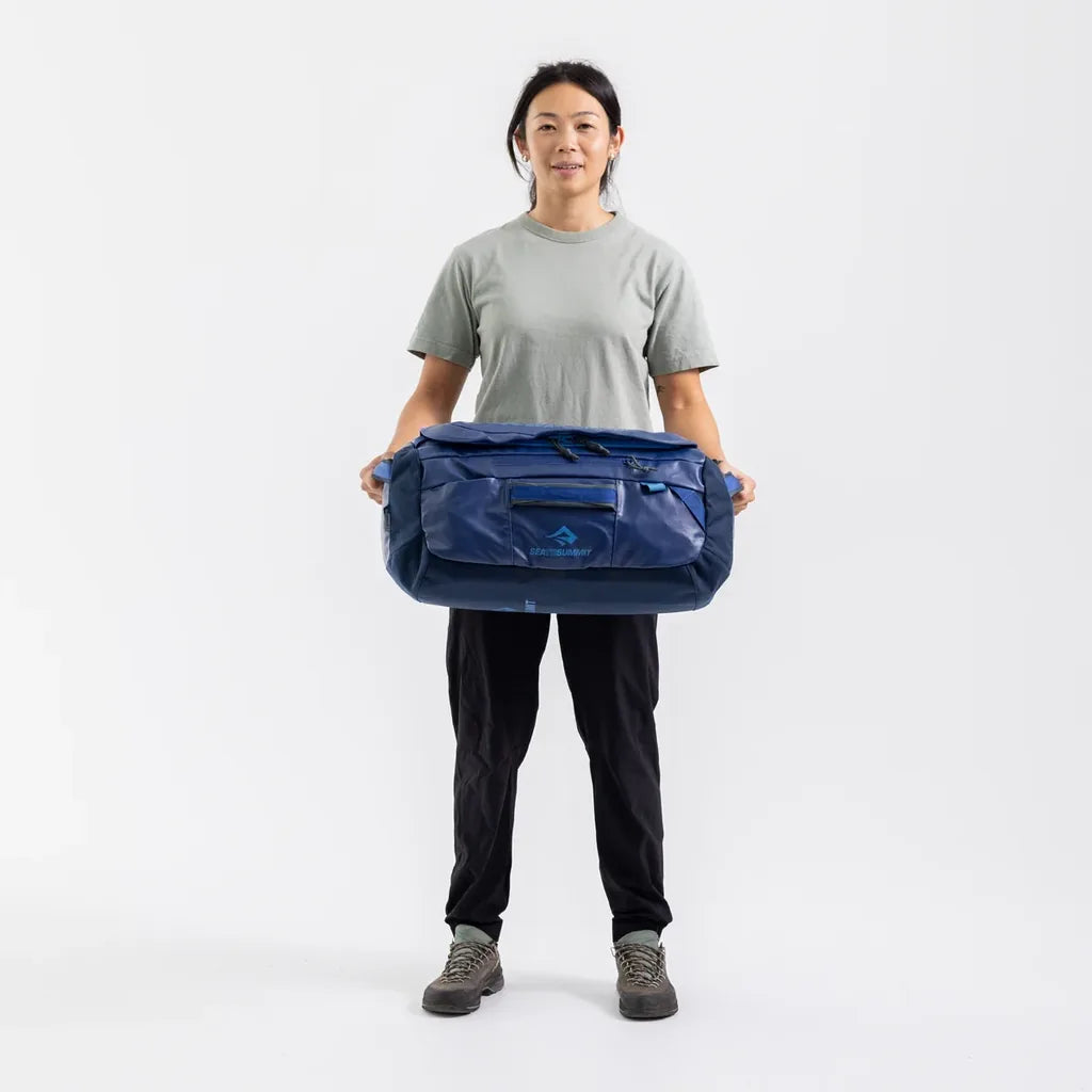 Woman holding a navy Sea to Summit Meridian Duffle Bag in front of her to show its size