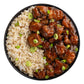 Sly Foods General Tao prepared meal top-down view on white background showing a black bowl filled with glazed plant-based protein pieces in rich brown sauce alongside brown rice, garnished with sliced green onions