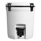 Stanley Adventure Fast Flow Water Jug 2 Gallon in Twilight front hero on white background showing navy blue cylindrical body with Stanley winged bear embossed logo, orange fast-flow spigot with lever handle at the front base, and orange latch hardware securing the lid