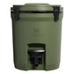 Stanley Adventure Fast Flow Water Jug 2 Gallon in Dried Pine front hero on white background showing olive green cylindrical body with Stanley winged bear embossed logo, black fast-flow spigot with lever handle at the front base, and black latch hardware securing the lid