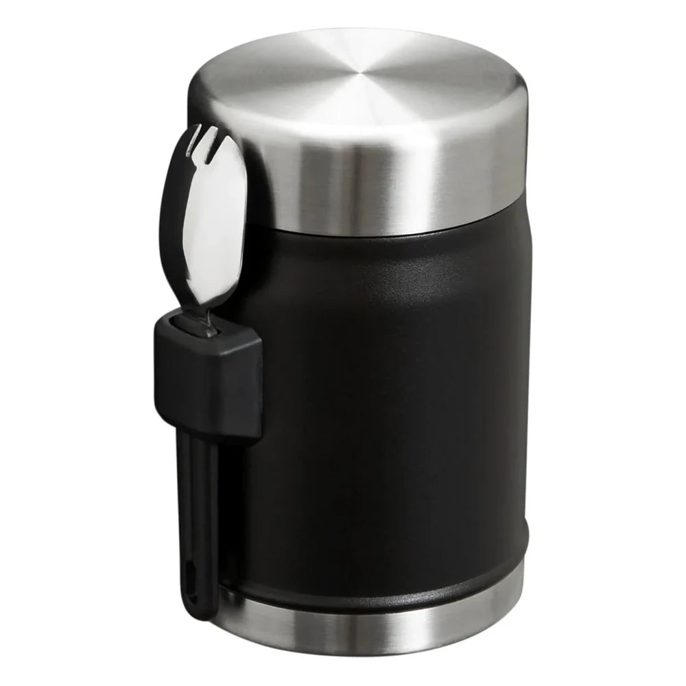 Stanley Adventure To-Go Food Jar and Spork 24oz in Matte Black top and side angle view on white background showing polished stainless steel lid, matte black jar body, black spork holder strap, and black spork clipped to the side