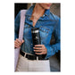 Stanley AeroLight Transit Bottle 20oz in Black lifestyle shot showing a woman in a denim shirt carrying a pink tote bag while holding the matte black bottle with Stanley logo at her side in an urban setting