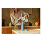 Stanley AeroLight Transit Bottle 20oz in Light Blue lifestyle shot in a modern kitchen showing a woman in a gray cardigan pouring coffee from a white Stanley carafe into the open light blue bottle on a white countertop with the lid set to the side