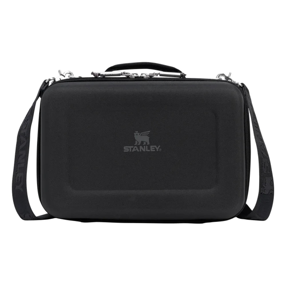 Stanley All Day Midi Lunch Box 6.3QT in Black front hero on white background showing black hard-shell EVA lunch box with black textured exterior, Stanley winged bear logo embossed on the front panel, top carry handle with zipper pulls, and black Stanley-branded shoulder strap attached to side D-rings