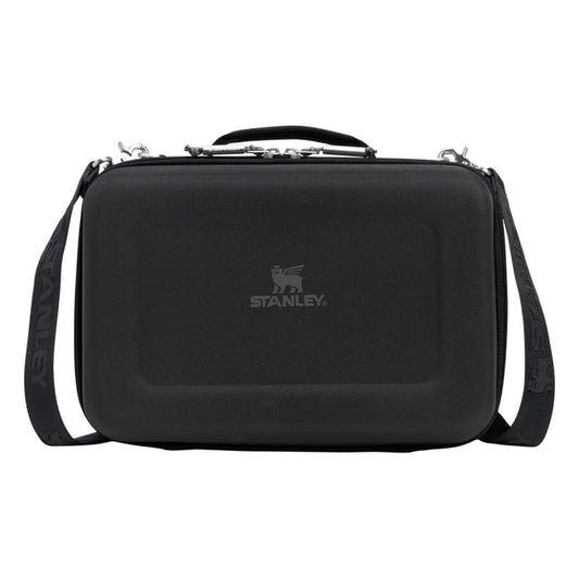 Stanley All Day Midi Lunch Box 6.3QT in Black front hero on white background showing black hard-shell EVA lunch box with black textured exterior, Stanley winged bear logo embossed on the front panel, top carry handle with zipper pulls, and black Stanley-branded shoulder strap attached to side D-rings