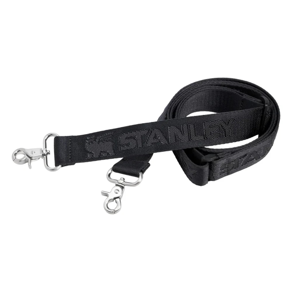 Stanley All Day Midi Lunch Box 6.3QT shoulder strap detail on white background showing the black woven nylon Stanley-branded strap with embossed Stanley text and winged bear logo, coiled with two silver carabiner-style swivel clips at each end for attaching to the lunch box D-rings