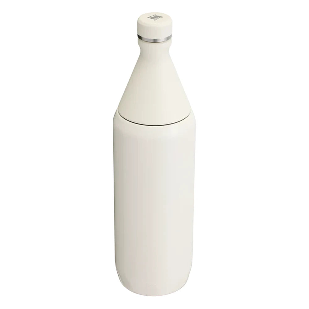 Stanley All Day Slim Bottle 34oz in Cream Gloss back view on white background showing smooth creamy white gloss cylindrical body, tapered cone neck, flat cap with Stanley bear icon on top, and stainless steel trim ring at the neck