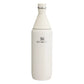 Stanley All Day Slim Bottle 34oz in Cream Gloss front hero on white background showing creamy white gloss tapered slim bottle with cone-shaped neck, flat screw cap with Stanley winged bear icon, engraved Stanley winged bear logo on body, and stainless steel trim ring at the neck