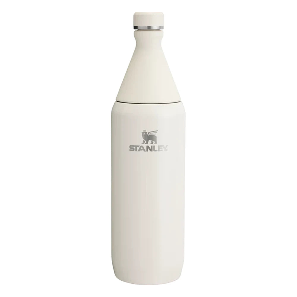 Stanley All Day Slim Bottle 34oz in Cream Gloss front hero on white background showing creamy white gloss tapered slim bottle with cone-shaped neck, flat screw cap with Stanley winged bear icon, engraved Stanley winged bear logo on body, and stainless steel trim ring at the neck