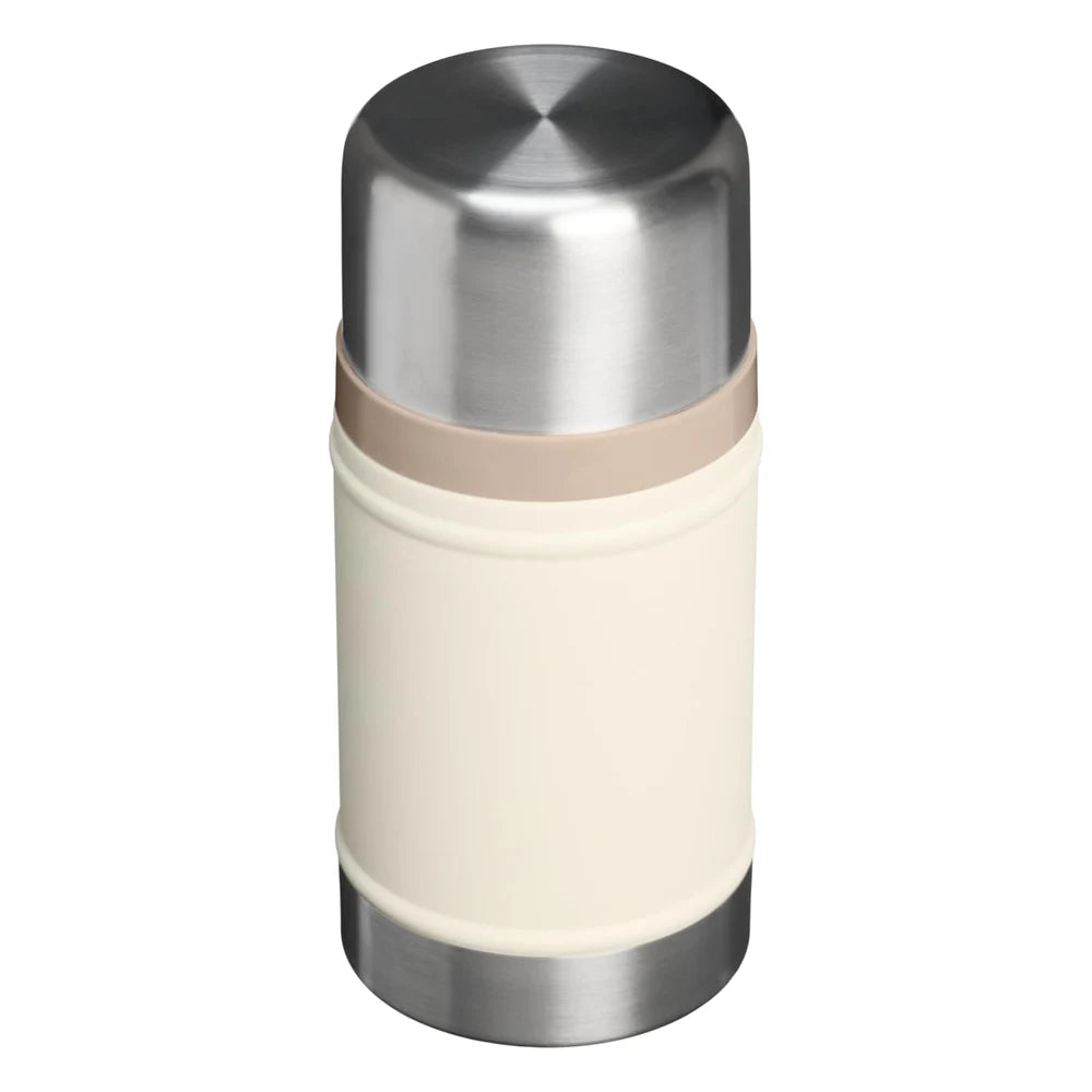 Stanley Classic Legendary Food Jar 24oz in Cream three-quarter elevated view on white background showing cream matte cylindrical body, large polished stainless steel dome lid from above, tan beige rubber gasket ring at the lid-body junction, and brushed stainless steel base