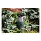 Stanley Classic Legendary Food Jar 24oz in Hammertone Green lifestyle shot outdoors showing the open jar with stainless steel wide-mouth opening filled with fresh dark cherries, Stanley Since 1913 logo on the hammertone green textured body, set among green garden foliage with a hand dropping cherries in from above
