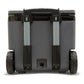 Stanley The Cold For Days Wheeled Outdoor Cooler 50QT in Charcoal Black back view on white background showing the fully extended two-stage aluminum telescoping handle with black grip, gray charcoal body with black lid trim, two large black all-terrain wheels with dimpled rubber tread, and drain plug with tethered cap at the bottom center