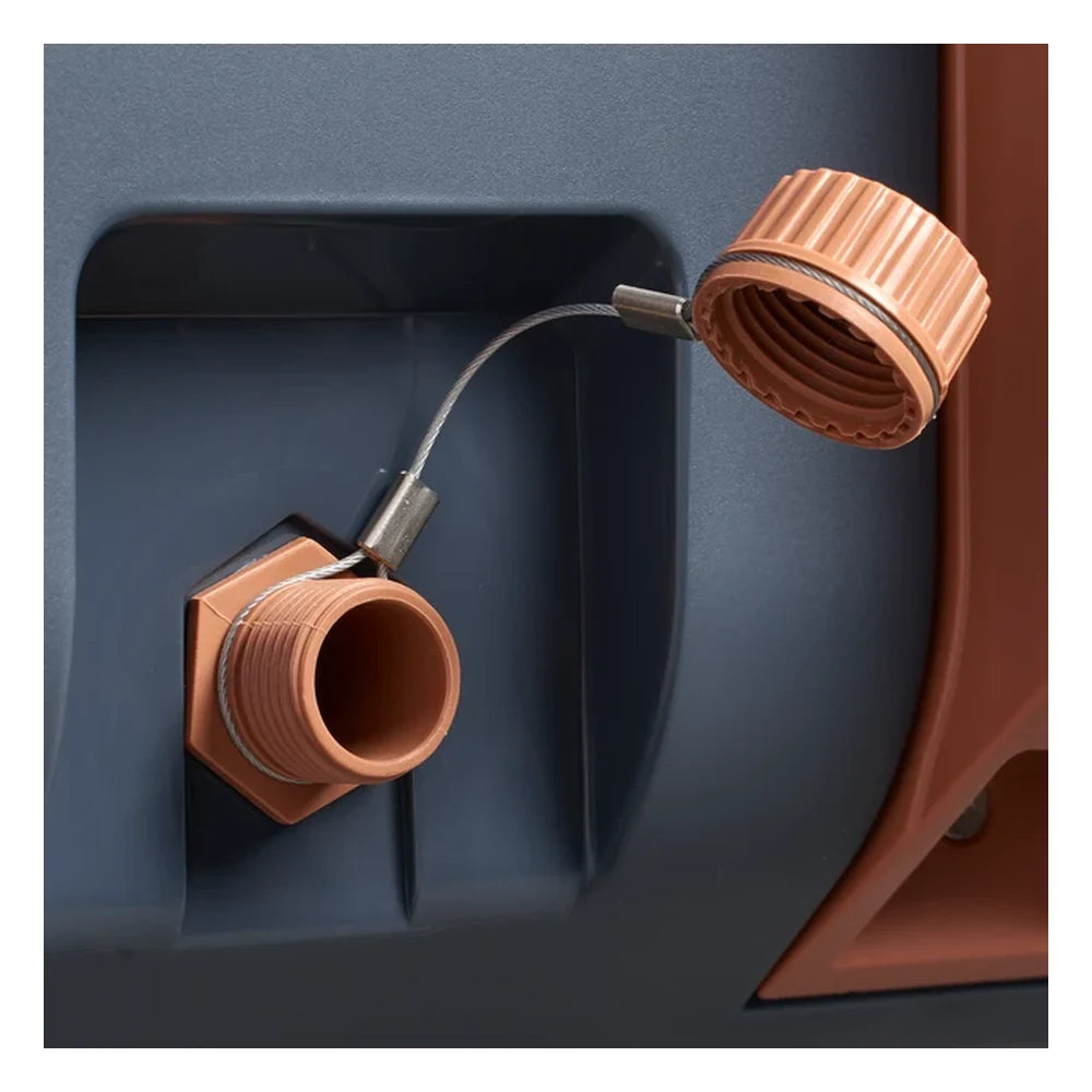 Stanley The Cold For Days Wheeled Outdoor Cooler 50QT in Twilight close-up detail on white background showing the drain plug open with threaded orange hex drain fitting and ribbed orange screw cap swung to the side on its stainless steel cable tether, recessed in the navy blue body