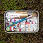 Stanley Legendary Useful Box 1.25 QT holding paint tubes and brushes outdoors on mossy ground