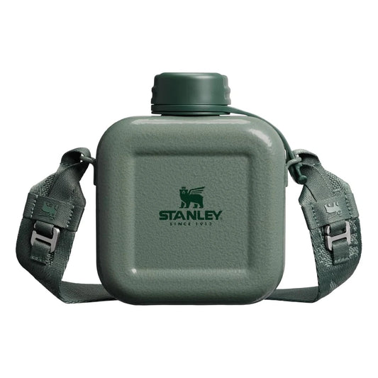 Stanley Next X Nature Canteen in Hammertone Green front hero on white background showing square hammertone green enamel body with Stanley Since 1913 winged bear logo, green screw-top cap with tether cord, and adjustable dark green woven nylon shoulder strap with metal quick-release buckles on both sides