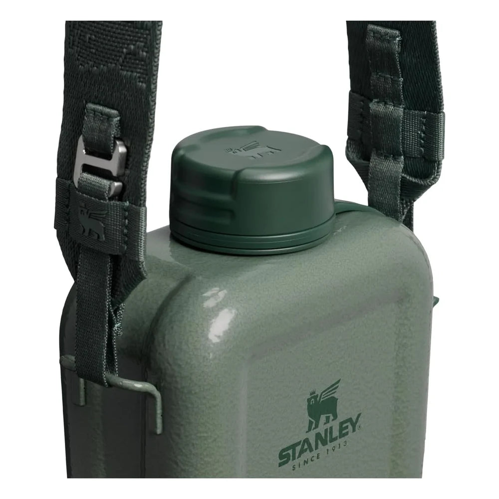 Stanley Next X Nature Canteen in Hammertone Green close-up top detail on white background showing the dark green woven nylon adjustable shoulder strap with metal quick-release buckles attached to the canteen, green screw-top cap with Stanley winged bear icon on top, and hammertone green enamel body with Stanley Since 1913 logo