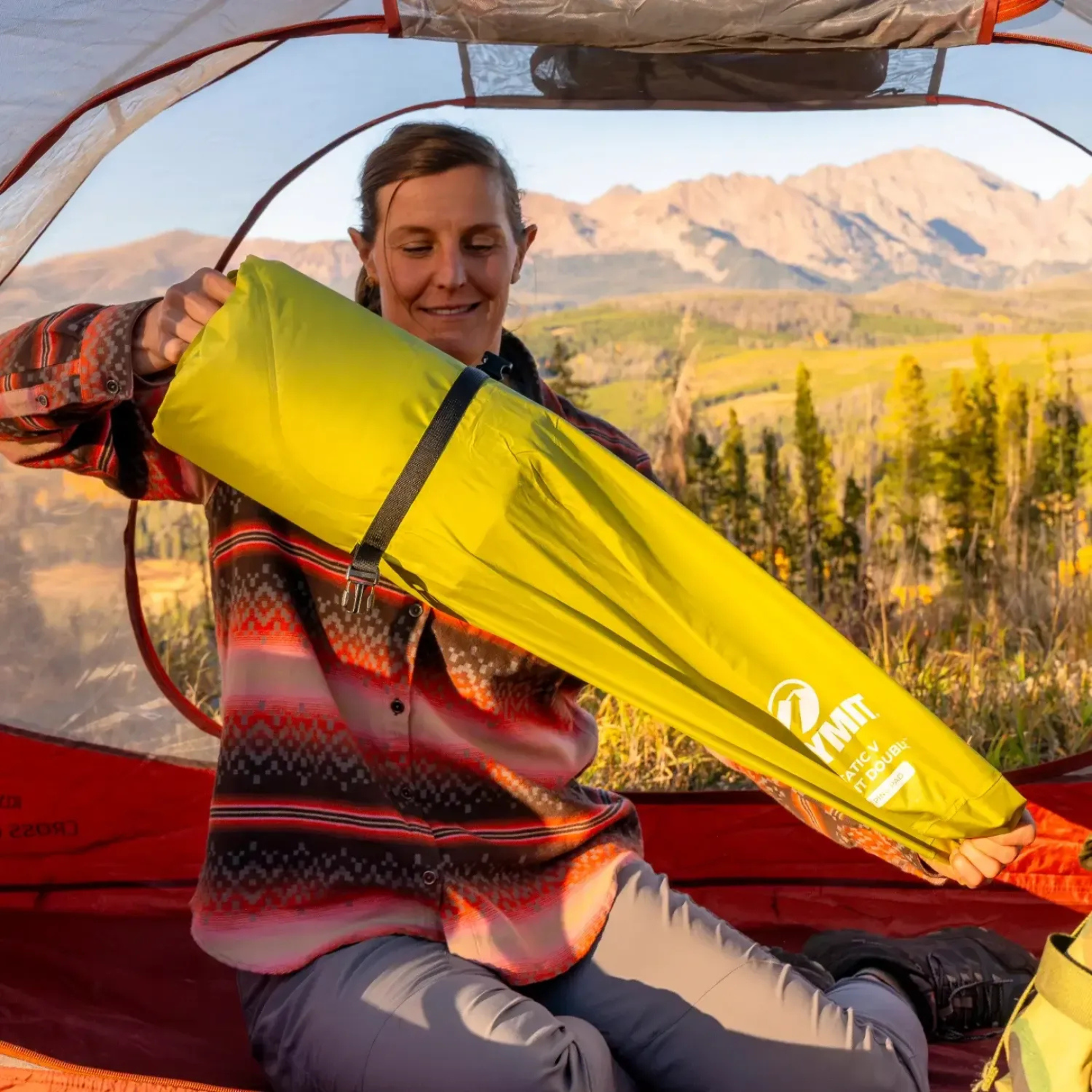 Camper unrolling Klymit Static V Summit Double sleeping pad inside tent